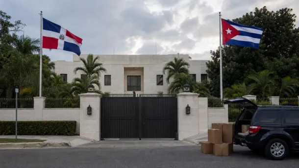 Representación editorial de las banderas de República Dominicana y Cuba frente a una sede diplomática